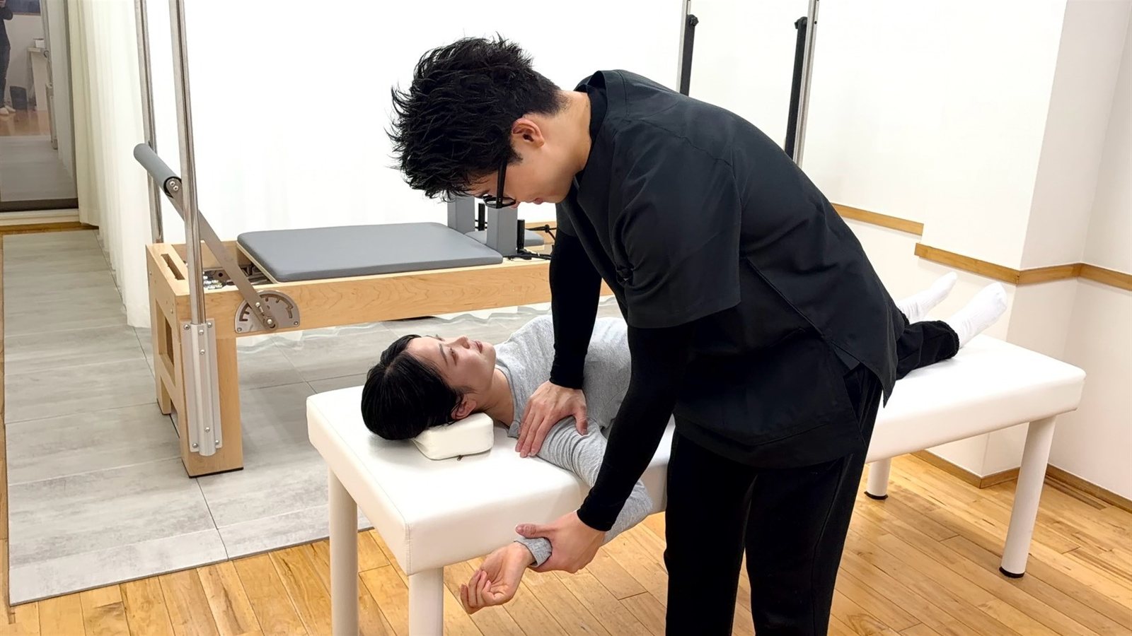 あおむけのお客様の腕を動かして肩まわりをのばす理学療法士