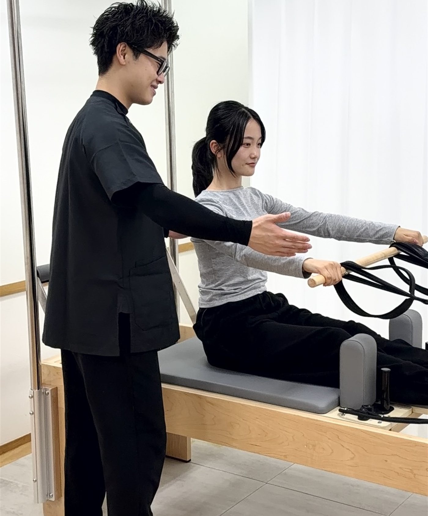 マシンピラティスで姿勢を確かめる理学療法士とお客様